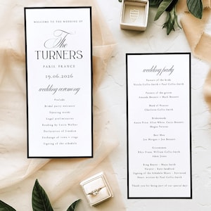 May include: Wedding stationery with two black-bordered cards displaying event details, including "The Turners" and "wedding party." A ring box and ring are present, alongside greenery and fabric, creating an elegant aesthetic.