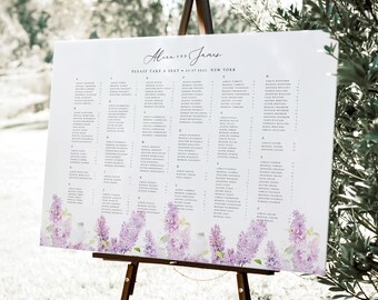 Op de afbeelding: Een witte trouwzittingstafel op een houten ezel. De kaart heeft een bloemenontwerp van paarse bloemen aan de onderkant en een lijst met namen. De tekst luidt "Alice and Jane" en "Please take a seat - 24.07.2022 New York."