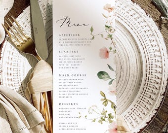May include: A white menu card with a floral design and a handwritten menu listing appetizers, starters, main course, and desserts. The menu includes dishes like creamy ricotta polenta cake, grilled filet with red onion marmalade, grilled salmon with citrus basil relish, and wedding cake tiers of chocolate chip cake and banana cake.