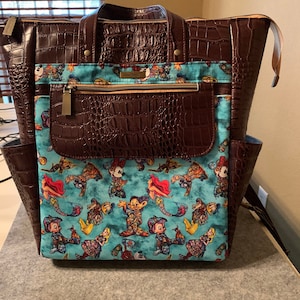 May include: A brown faux leather backpack with a zippered front pocket and a blue and white fabric lining featuring a pattern of Disney characters.
