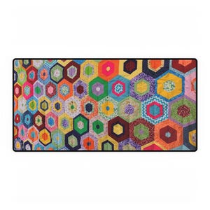 Puede incluir: Un edredón rectangular de retazos colorido con un patrón hexagonal repetido. El edredón muestra una vibrante gama de colores, incluyendo rojo, naranja, amarillo, verde, azul, morado y rosa. Cada hexágono está relleno con diferentes telas estampadas.