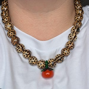 TOMATINA - Statement Necklace Leopard Ceramic Beads & Glass Tomato Pendant – Bold Summer Jewelry – Handmade Necklace – Playful Gift
Round ceramic beads in a wild leopard print radiate fierce vibes, while the glossy tomato-shaped glass pendant adds an unexpected, pop of juicy charm. A true statement piece that doesn’t take itself too seriously: ideal for confident looks with a sense of humor, sultry Italian summer nights, or anyone who loves to wear their passion and wild side with a wink.