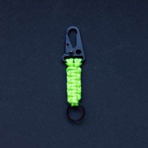 May include: A lime green paracord keychain with a black metal clip and a silver ring.