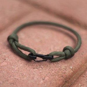 Peut inclure: Un bracelet en paracorde vert avec un fermoir en métal noir.