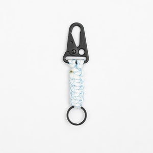 May include: A white and blue paracord keychain with a black metal clip and a black metal ring.