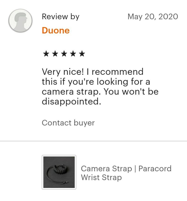May include: A black camera strap made of paracord. The strap is adjustable and has a buckle closure. The strap is shown wrapped around a wrist.