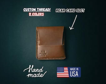 May include: A brown leather wallet with a rear card slot. The wallet is handmade in the USA and has the text "Hand made" and "Made in USA" on it. The wallet is available in 11 colors.