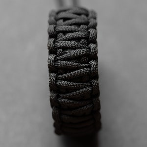 May include: A black paracord bracelet with a woven design.