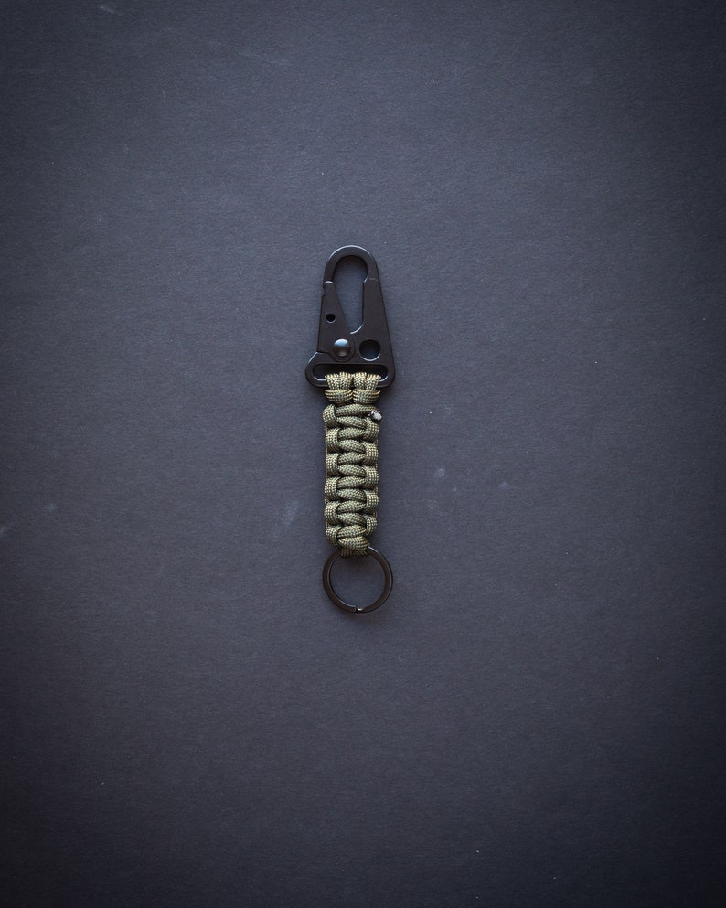 May include: A green and black paracord keychain with a metal carabiner and a key ring.