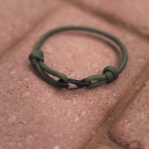 Pode incluir: Um bracelete de paracord verde com um fecho preto.