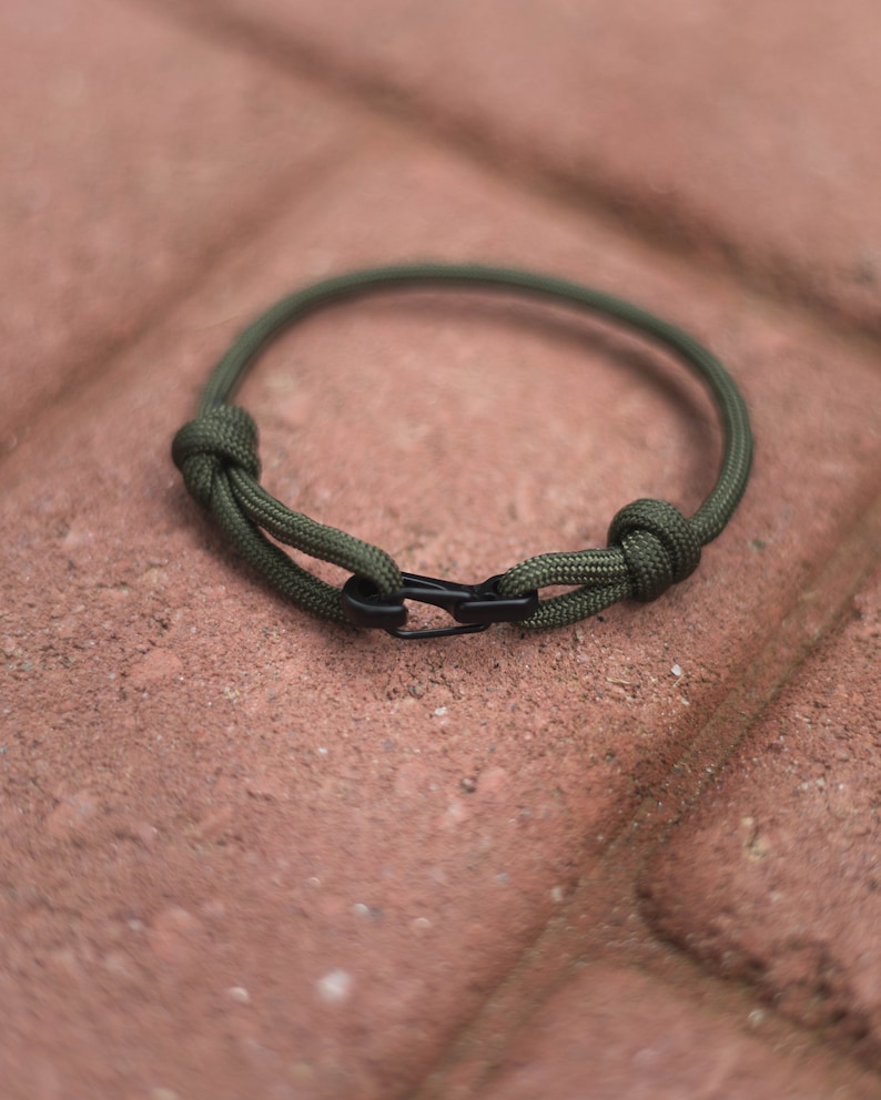Pode incluir: Um bracelete de paracord verde com um fecho preto.