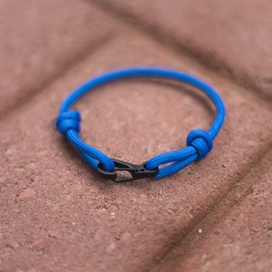 Pode incluir: Um bracelete de paracord azul com um fecho preto.