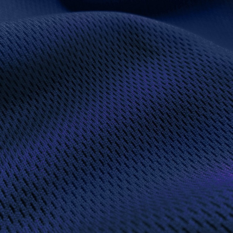 May include: Close-up of a dark blue fabric with a textured, mesh-like pattern. The fabric has a slight sheen and is soft to the touch.