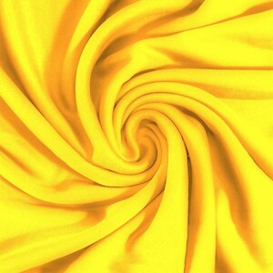 May include: A close-up of a bright yellow fabric, with a swirling pattern, creating a textured and dynamic visual.