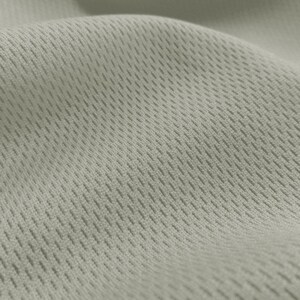 May include: Close-up of a light gray fabric with a textured, woven pattern. The fabric has a subtle sheen and a soft, breathable feel.