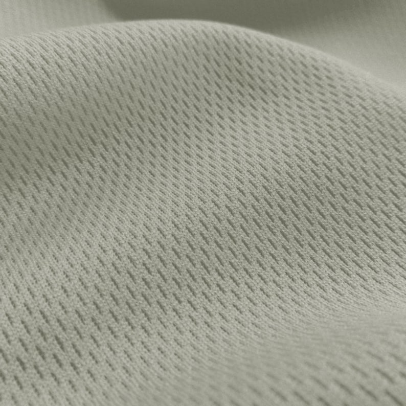 May include: Close-up of a light gray fabric with a textured, woven pattern. The fabric has a subtle sheen and a soft, breathable feel.