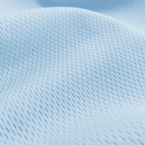 May include: Close-up of a light blue fabric with a textured, woven pattern. The fabric has a soft, smooth feel.
