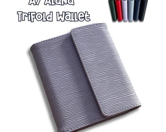 May include: A light purple A7 Alana trifold wallet with a textured, wavy line pattern on the exterior. The wallet features a flap closure and is displayed alongside a small row of seven additional wallets in various solid colours.