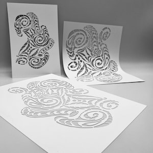 Puede incluir: Tres hojas de papel blancas con intrincados diseños recortados de patrones en espiral. Los diseños son similares pero únicos, creando un ritmo visual.