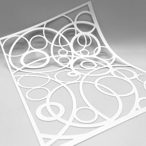 Peut inclure: Découpe de papier blanche avec un motif de cercles qui se chevauchent. Les cercles sont de tailles différentes et créent un motif géométrique abstrait.