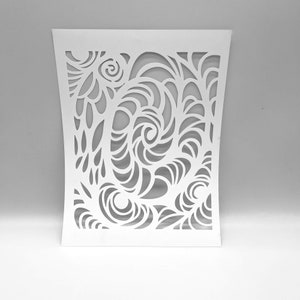 May include: A white, laser-cut decorative panel with an intricate swirling design. The pattern features stylized floral and wave-like shapes, creating a flowing, organic aesthetic. The panel has a curved shape and is suitable for home decor.