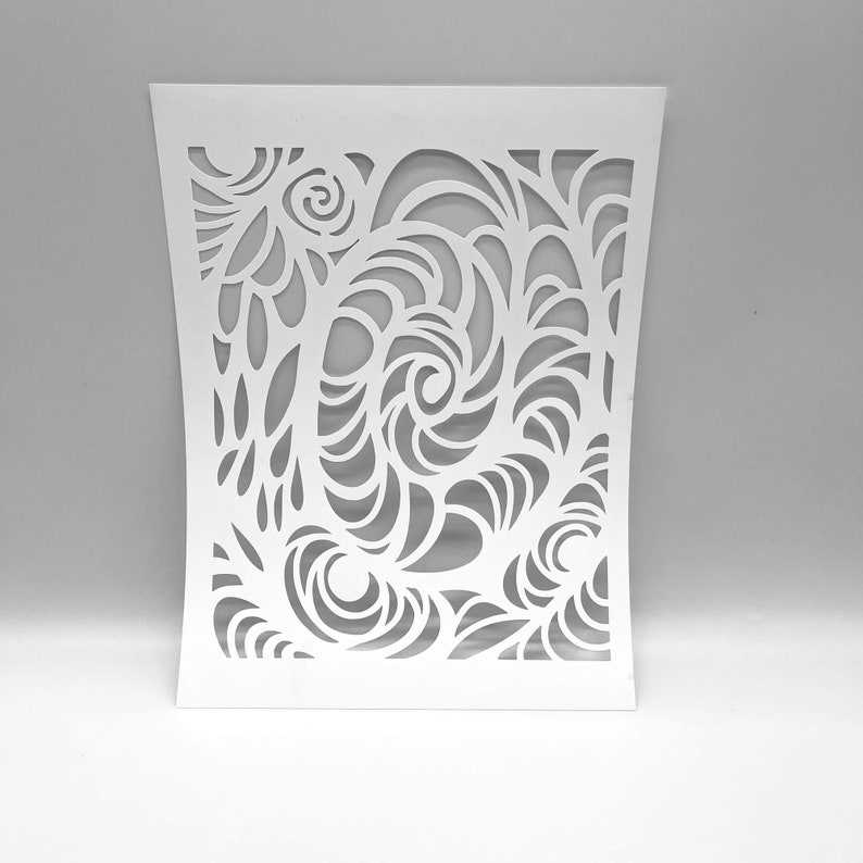 May include: A white, laser-cut decorative panel with an intricate swirling design. The pattern features stylized floral and wave-like shapes, creating a flowing, organic aesthetic. The panel has a curved shape and is suitable for home decor.