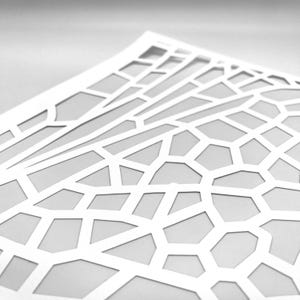 Könnte beinhalten: Ein weißes Papier mit einem geometrischen Muster aus miteinander verbundenen Linien und Formen. Das Design zeigt ein Netzwerk aus unregelmäßigen Polygonen und linearen Elementen, wodurch ein geschichteter Effekt entsteht. Das Papier ist leicht gebogen.