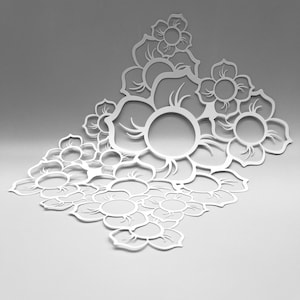 May include: A white, laser-cut floral design with multiple flower shapes and leaves. The design is intricate, with open centres in the larger flowers. The overall shape is a stylized arrangement, suitable for decorative purposes.