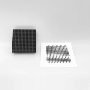 May include: A black rubber stamp with a grid pattern and small circles. The stamp is used to create a grid pattern with small circles on paper.
