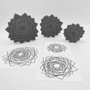 May include: A collection of geometric art pieces in grayscale. The image features three-dimensional star-shaped objects and corresponding two-dimensional prints. The designs consist of intricate, spiraling line patterns within a starburst frame.