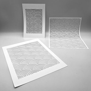 May include: Three white paper cutouts featuring a repeating wave pattern. The cutouts are rectangular and square, with the wave design creating a layered, textured effect. The paper is clean and crisp, with the cut-out design creating shadows.
