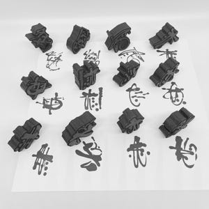May include: A collection of black, three-dimensional stamps with intricate designs, scattered on a white surface. The stamps have been used to create black ink impressions of Chinese characters. The image is a top-down view, with the stamps and impressions clearly visible.
