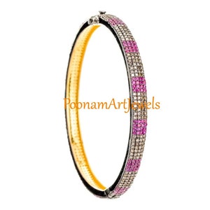 Pode incluir: Um bracelete de prata com uma fila de pedras preciosas cor-de-rosa e uma fila de pedras preciosas transparentes. O bracelete está sobre um fundo branco.