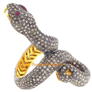 Könnte beinhalten: Ein goldener und silberner Schlangenring mit einem Rubinauge und pavé-besetzten Diamanten. Der Ring ist so konzipiert, dass er sich um den Finger legt.