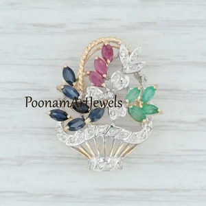 Op de afbeelding: Een gouden, zilveren en smaragdgroene bloemenbroche met een mandontwerp. De broche heeft blauwe saffieren, rode robijnen en witte diamanten. De tekst "PoonamArtJewels" is zichtbaar in de afbeelding.
