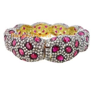 Pode incluir: Um bracelete de prata com um design texturizado com rubis vermelhos e diamantes brancos. O bracelete é aberto e tem um fecho de dobradiça.