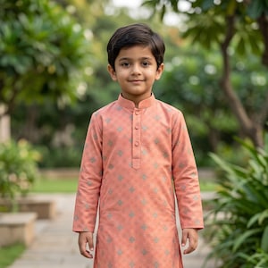 May include: A peach-colored long-sleeved kurta featuring a subtle plaid pattern with small grey geometric accents, a mandarin collar, and a button-down placket, paired with plain white trousers and light-colored slip-on shoes.