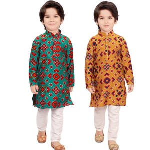 May include: Two young boys wearing traditional Indian clothing. The boys are wearing long-sleeved shirts with a geometric pattern and white pants. One shirt is teal with red and orange accents, and the other is mustard yellow with red and blue accents.