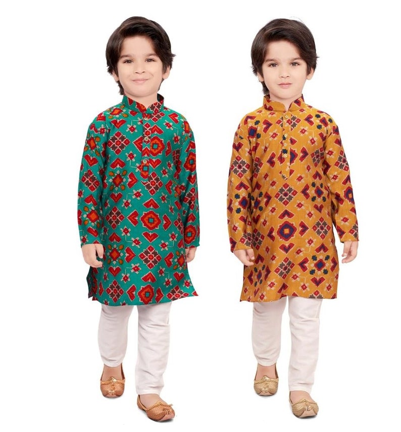 May include: Two young boys wearing traditional Indian clothing. The boys are wearing long-sleeved shirts with a geometric pattern and white pants. One shirt is teal with red and orange accents, and the other is mustard yellow with red and blue accents.