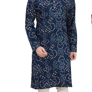 May include: A navy blue long-sleeved shirt with a white and multi-colored patterned design. The shirt has a mandarin collar and a button closure. The model is wearing white pants and brown shoes.