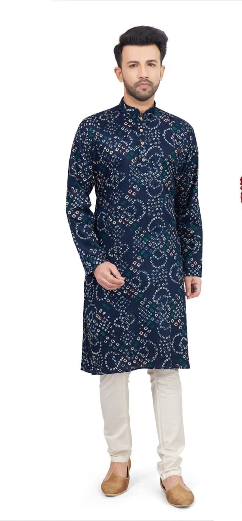 May include: A navy blue long-sleeved shirt with a white and multi-colored patterned design. The shirt has a mandarin collar and a button closure. The model is wearing white pants and brown shoes.