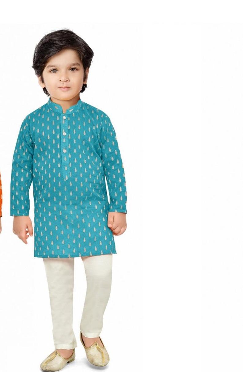 May include: A young boy wearing a teal blue kurta with a white pattern and white trousers. He is wearing gold shoes.
