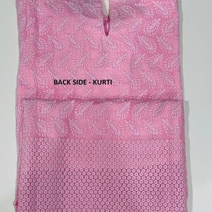 May include: A pink cotton kurti with a delicate floral pattern and a lace trim. The back of the kurti has a keyhole opening at the neckline. The text "BACK SIDE - KURTI" is printed on the back of the garment.
