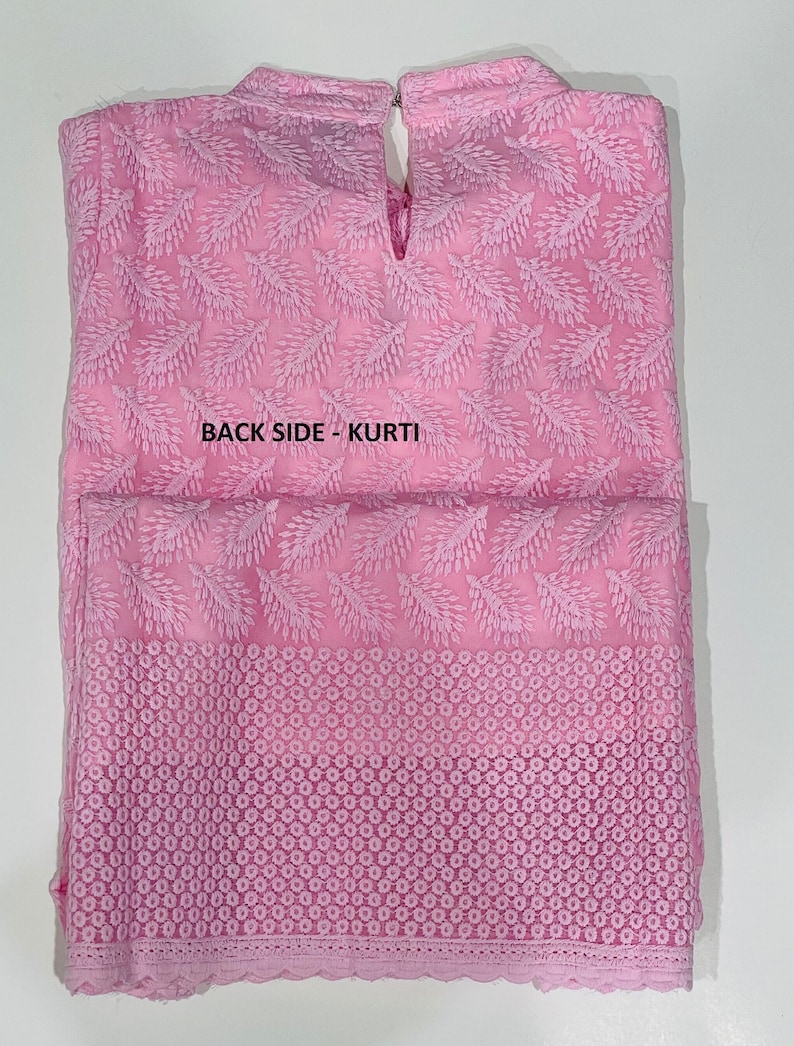 May include: A pink cotton kurti with a delicate floral pattern and a lace trim. The back of the kurti has a keyhole opening at the neckline. The text "BACK SIDE - KURTI" is printed on the back of the garment.