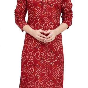 May include: A maroon long-sleeved kurta with a white and red geometric pattern. The kurta has a mandarin collar and a button closure. The model is wearing white pants and maroon shoes.