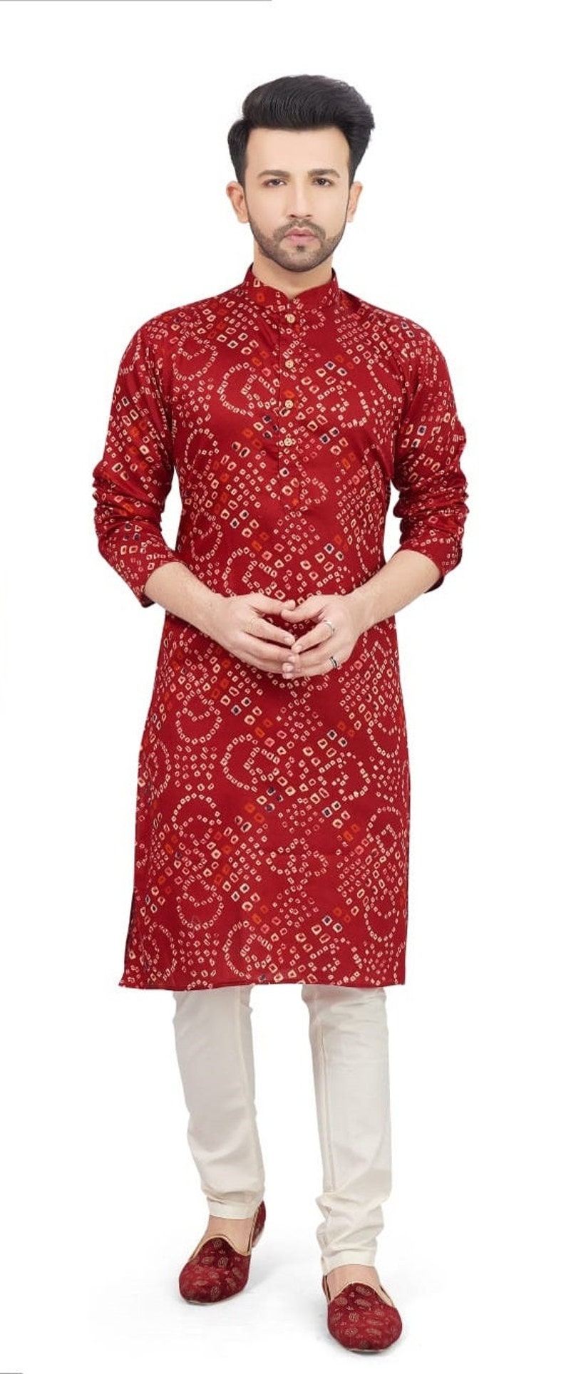 May include: A maroon long-sleeved kurta with a white and red geometric pattern. The kurta has a mandarin collar and a button closure. The model is wearing white pants and maroon shoes.
