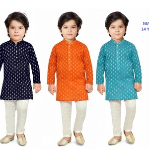 May include: Three young boys wearing traditional Indian clothing called kurtas. The kurtas are in three different colours: navy blue, orange, and teal. Each kurta has a white pattern. The boys are wearing white trousers and brown shoes.