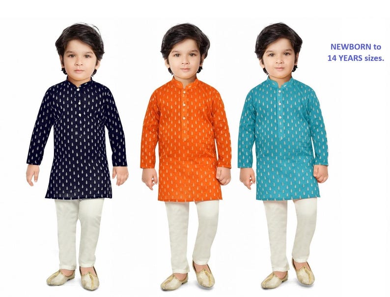 May include: Three young boys wearing traditional Indian clothing called kurtas. The kurtas are in three different colours: navy blue, orange, and teal. Each kurta has a white pattern. The boys are wearing white trousers and brown shoes.
