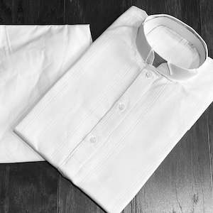 May include: A white collared shirt with a striped pattern and a white undershirt. The shirt has a mandarin collar and two buttons.