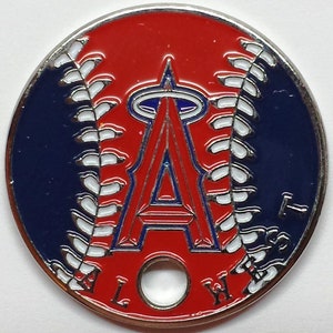 May include: A red, white, and blue baseball-themed coin with the Los Angeles Angels logo. The coin has a hole in the center and the words "AL West" around the edge.